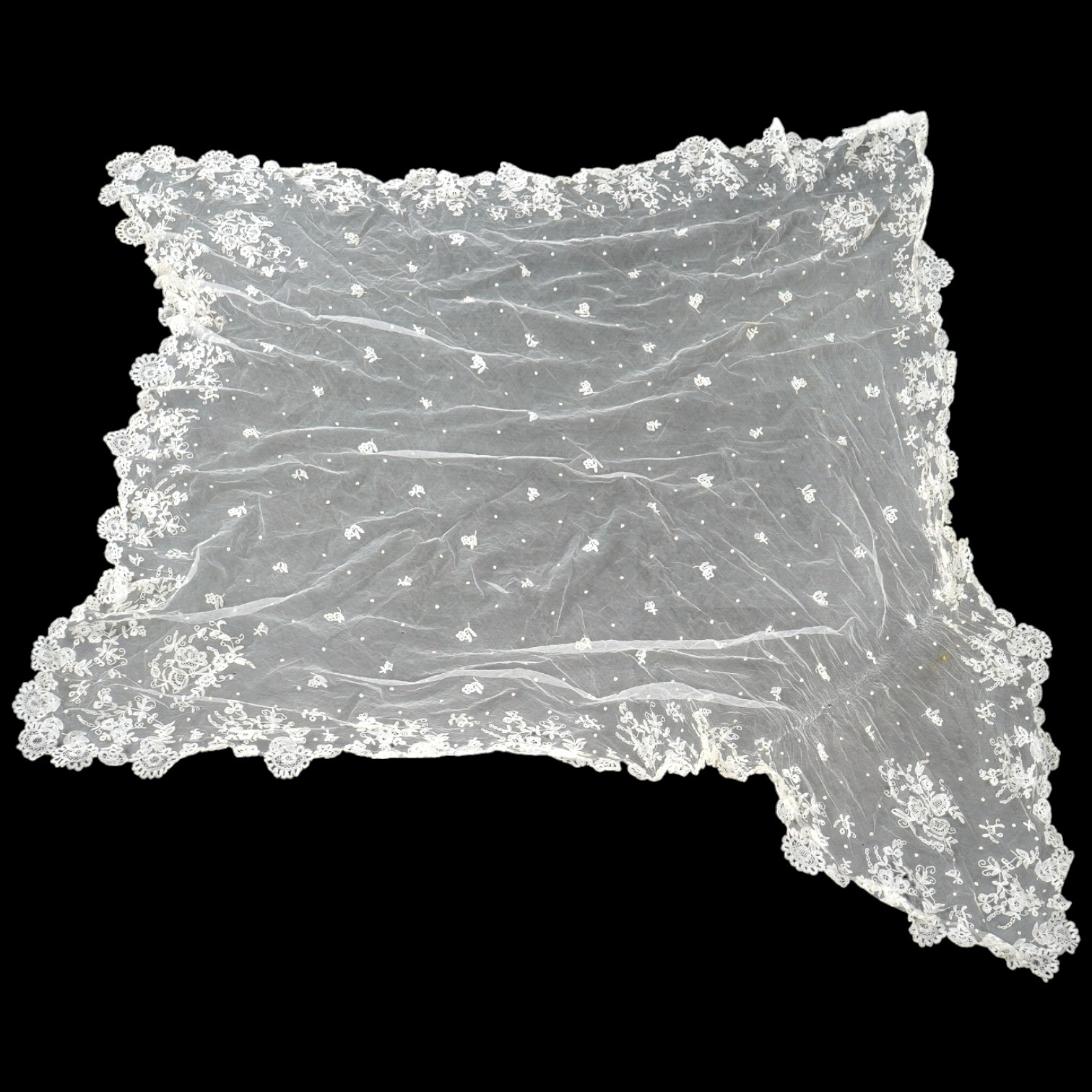 A late Edwardian hand bobbin lace Honiton and net wedding veil, approximately 248cm x 230cm. Condition - one corner has corner has been attached to a hair comb and damaged the netting.